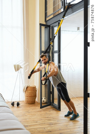 Athletic young man doing exercise with resistance band Athletic young man doing exercise with resistance band 75874876