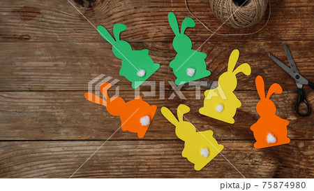 Easter bunnies made of paper on a wooden background. Create a decor for easter 75874980