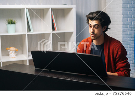 Portrait of music teacher explains to student how to play piano during lesson. 75876640