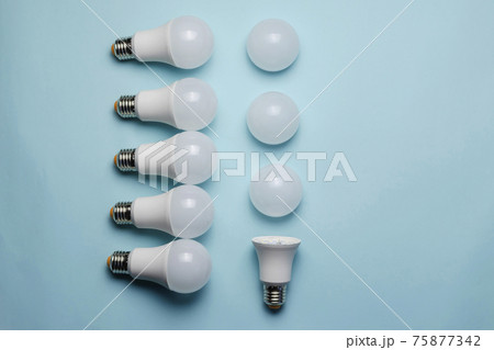 Creative geometric composition with LED lights on a blue background. One bulb without a diffuser, five new whole bulbs, and three white matte light diffusers. Flat lay 75877342