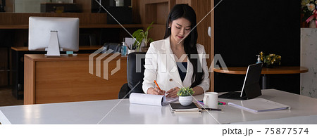 Business woman reading minute of meeting on her notebook in office. 75877574