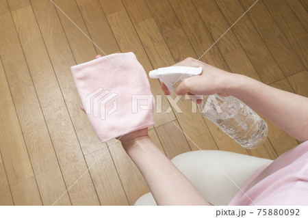 ピンクの雑巾にスプレーをする女性の手元 75880092