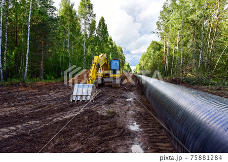 Excavator during earthwork for laying Crude oil and Natural gas pipeline in forest area.   75881284