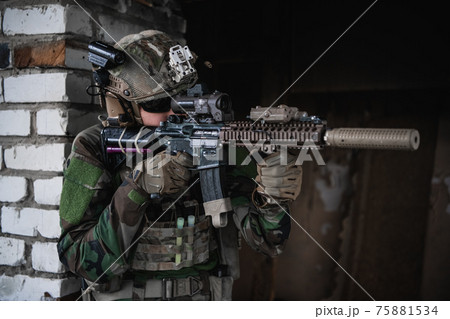 Military soldier in the form holds in the hands an assault rifle, check possible enemies around the corner 75881534