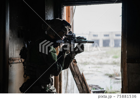 Soldier in full US MARSOC equipment entering abandoned building, aiming different angles with MK18 assault rifle 75881536