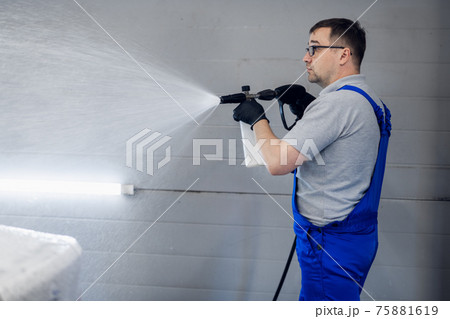 Car washing and detailing. Professional worker is washing a black car by pressure washer at a car wash. 75881619