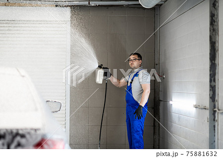 Worker covering automobile with foam at car wash. 75881632