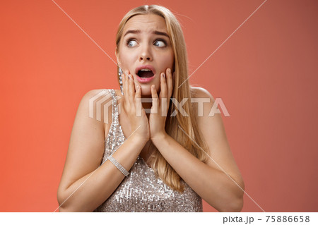 Afraid girl panic look left scared trembling fear insecure touching cheeks helpless stare sideways grimacing gasping frightened nervously waiting help, standing concerned red background 75886658