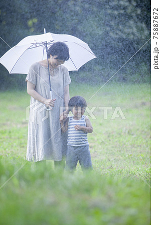 雨の日に傘をさして歩く親子 75887672