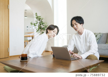 リビングでパソコンを見る夫婦 リビングでパソコンを見る夫婦 75889732