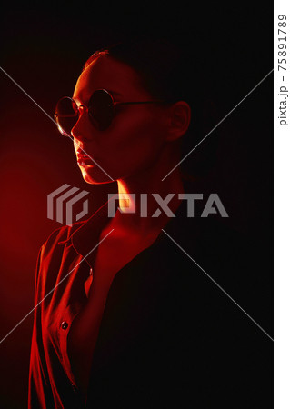 Beautiful young woman in sunglasses. in red light 75891789