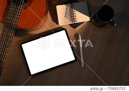 Mock up digital tablet, notebook, coffee cup and guitar on wooden floor in living room. 75893722