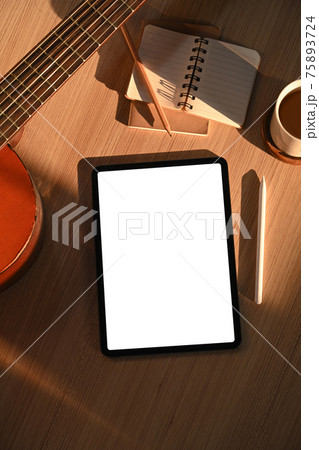 Overhead shot of digital tablet, notebook, coffee cup and acoustic guitar on wooden floor. 75893724