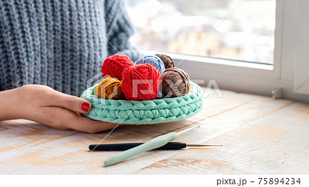 Woman holding knitted couch with yarn balls 75894234