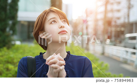 空を見上げて祈る女性 75894963