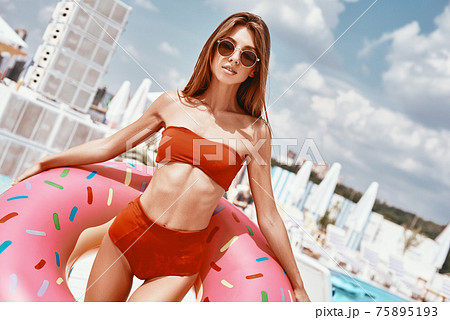To keep the body in good shape is a duty. Sexy woman is wearing red bikini and holding inflatable swim ring in shape of donut To keep the body in good shape is a duty. Sexy woman is wearing red bikini and holding inflatable swim ring in shape of donut 75895193