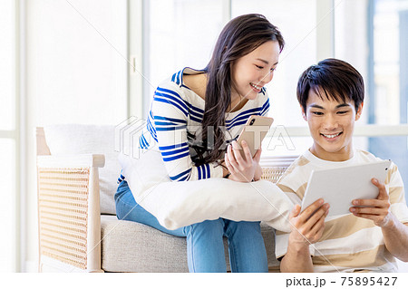 カップルでスマホとタブレットを操作している カップルでスマホとタブレットを操作している 75895427