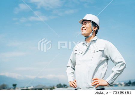 青空と作業服を着た男性 75896365