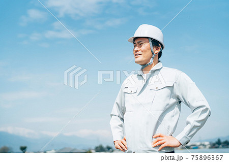 青空と作業服を着た男性 75896367