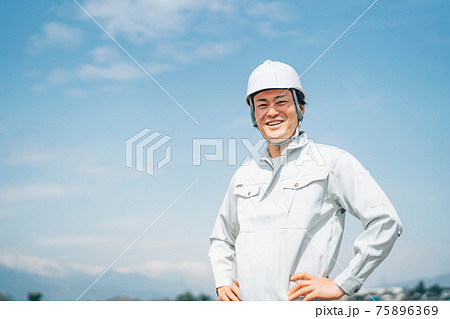 青空と作業服を着た男性 75896369