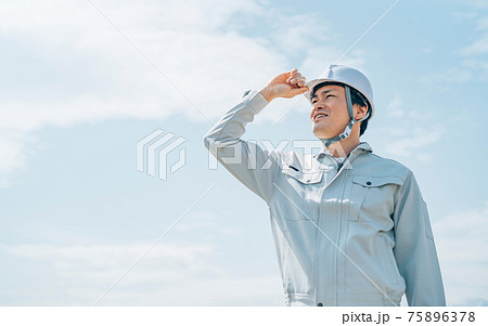 青空と作業服を着た男性 75896378