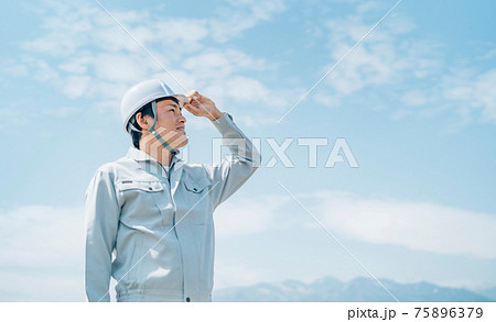 青空と作業服を着た男性 75896379