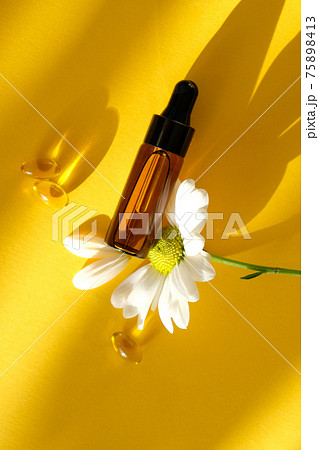 Aromatherapy composition on yellow background. Chamomile essential oil in a glass bottle with chamomile. 75898413