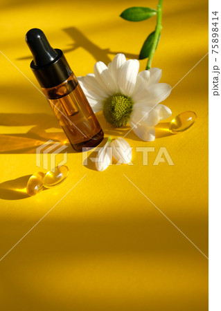 Aromatherapy composition on yellow background. Chamomile essential oil in a glass bottle with chamomile. 75898414