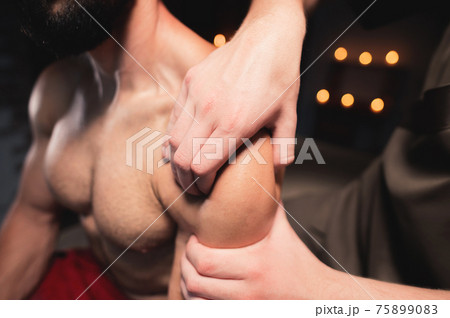 Close-up Professional sports shoulder massage. Male athlete receiving massage from male masseur Close-up Professional sports shoulder massage. Male athlete receiving massage from male masseur 75899083