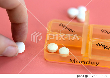 Pill box reminder, hand taking medicine daily pills in colorful box on pink background, elderly,senior,business,health,medication concept modern design 75899809