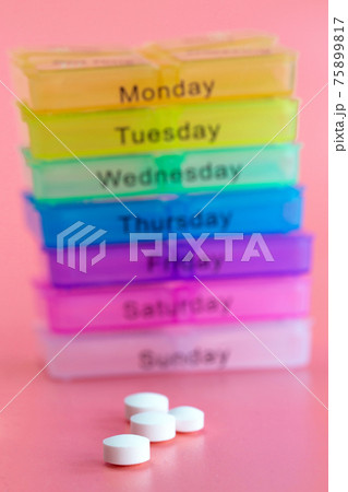 Pill box reminder, hand taking medicine daily pills in colorful box on pink background, elderly,senior,business,health,medication concept modern design 75899817