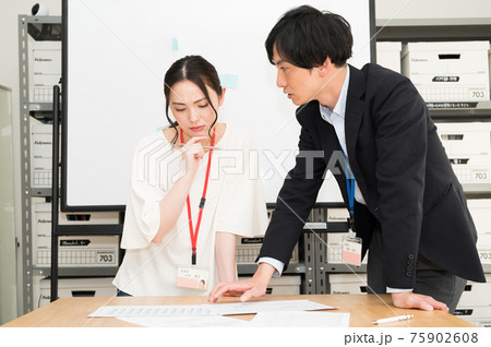 書類を見ながら女性社員にアドバイスする上司 書類を見ながら女性社員にアドバイスする上司 75902608