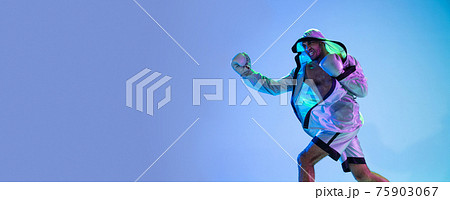 High-fashion styled man in white outfit pacticing box isolted over gradient background in neon light 75903067