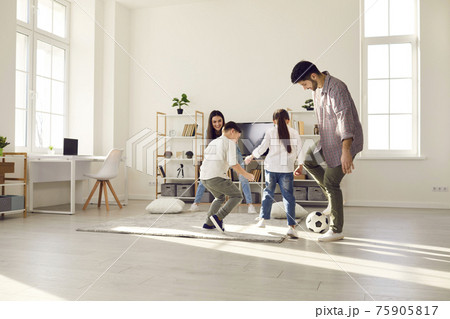 Happy family staying at home have fun together play football in living-room Happy family staying at home have fun together play football in living-room 75905817