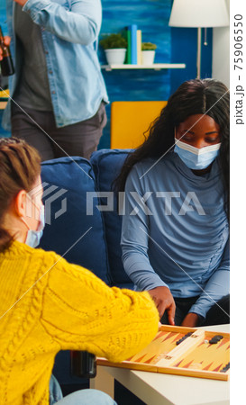 African woman competing with friends playing backgammon 75906550