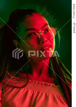 Young beautiful Asian girl isolated over red green neon light background. 75907966