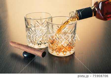 whiskey is poured into a glass from bottle 75908706