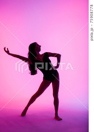 Professional ballerina dancing ballet in spotlights smoke. Beautiful young female wearing black bodysuit on floodlights background. 75908778