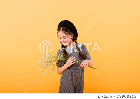 Funny child girl smiling with bouquet of flowers on a coloured background 75908815