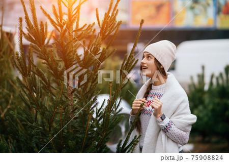 Woman with a white dog in her arms near a green Christmas trees Woman with a white dog in her arms near a green Christmas trees 75908824