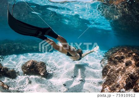 Freediving underwater in blue ocean. Sporty woman freediver swim with fins and corals. Freediving underwater in blue ocean. Sporty woman freediver swim with fins and corals. 75910912