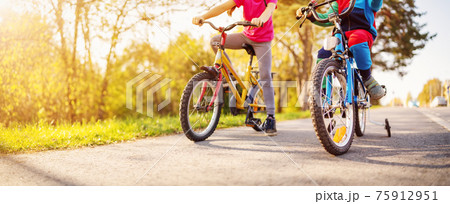 Cute children riding on bicycles on asphalt road in summer. 75912951