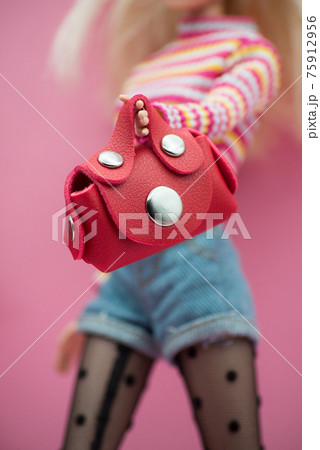 Closeup of mannequin doll wearing a jean's short, sexy black tights with a mini red leather bag in hand on pink background Closeup of mannequin doll wearing a jean's short, sexy black tights with a mini red leather bag in hand on pink background 75912956