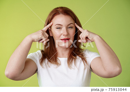 Smart choice. Intrigued thoughtful good-looking assertive redhead creative middle-aged woman touch temples squinting pondering info thinking use mental power read minds stand green background Smart choice. Intrigued thoughtful good-looking assertive redhead creative middle-aged woman touch temples squinting pondering info thinking use mental power read minds stand green background 75913044
