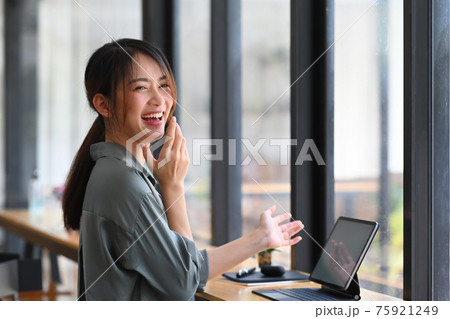 Happy young woman laughing while sitting at workplace. 75921249