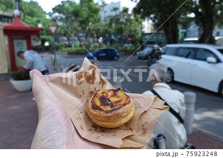 手に載せた、マカオの名物エッグタルト（街角の背景ボケ） 75923248
