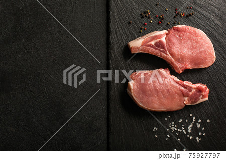 Uncooked Pork Chops on a stone kitchen cutting board. 75927797