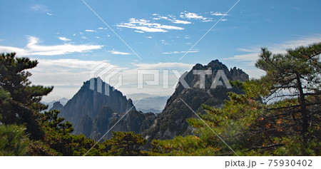 Huangshan Mountain in Anhui Province, China. View of Lotus Peak on right and Celestial Capital Peak on left from Bright Top. Scenic view of the highest peaks and trees on Huangshan Mountain, China. 75930402