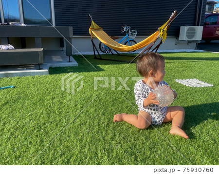 芝生の庭でボール遊びをする男の子の赤ちゃんの写真素材