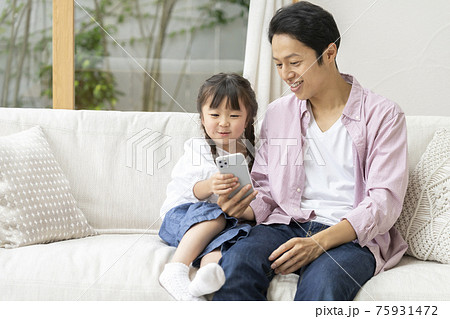スマートフォンを見る親子(父と娘)家族イメージ スマートフォンを見る親子(父と娘)家族イメージ 75931472